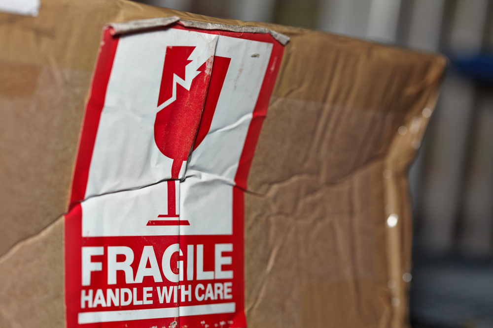 beat up cardboard box with a torn red and white FRAGILE lable on it representing importance of follow-up