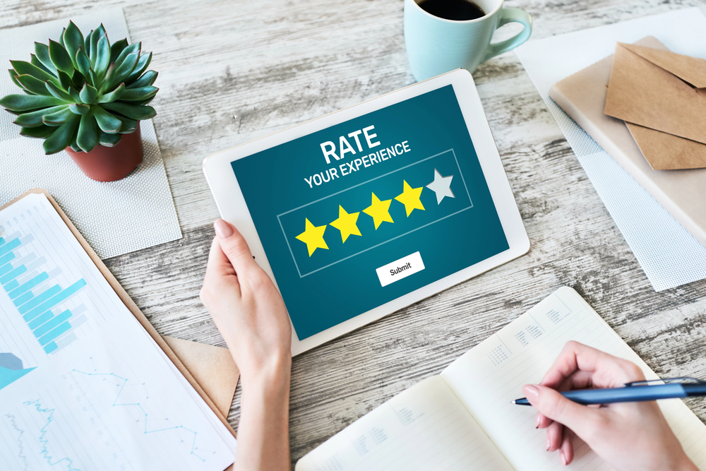 A woman's hand holding a computer tablet with a 4 star rating representing The Power of User-Generated Content.